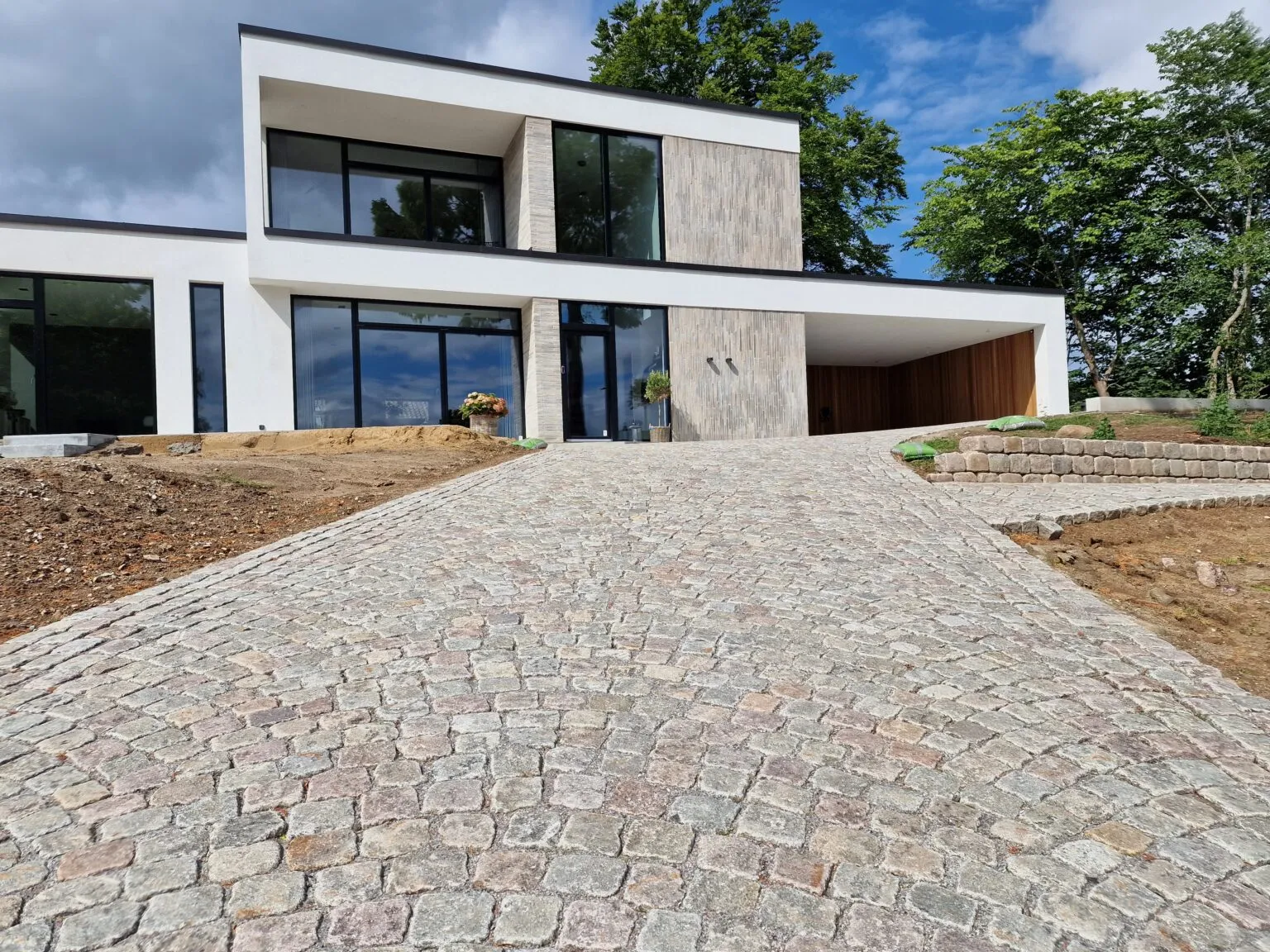 Indkørsel af genbrugte brosten foran moderne villa