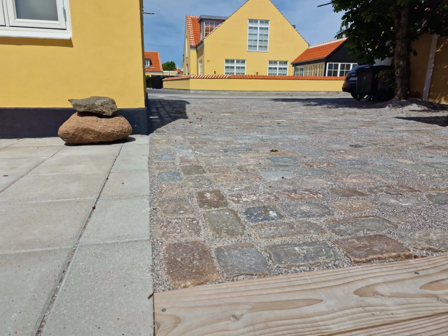 Brostensbelægning ved gult byhus i Skagen-stil
